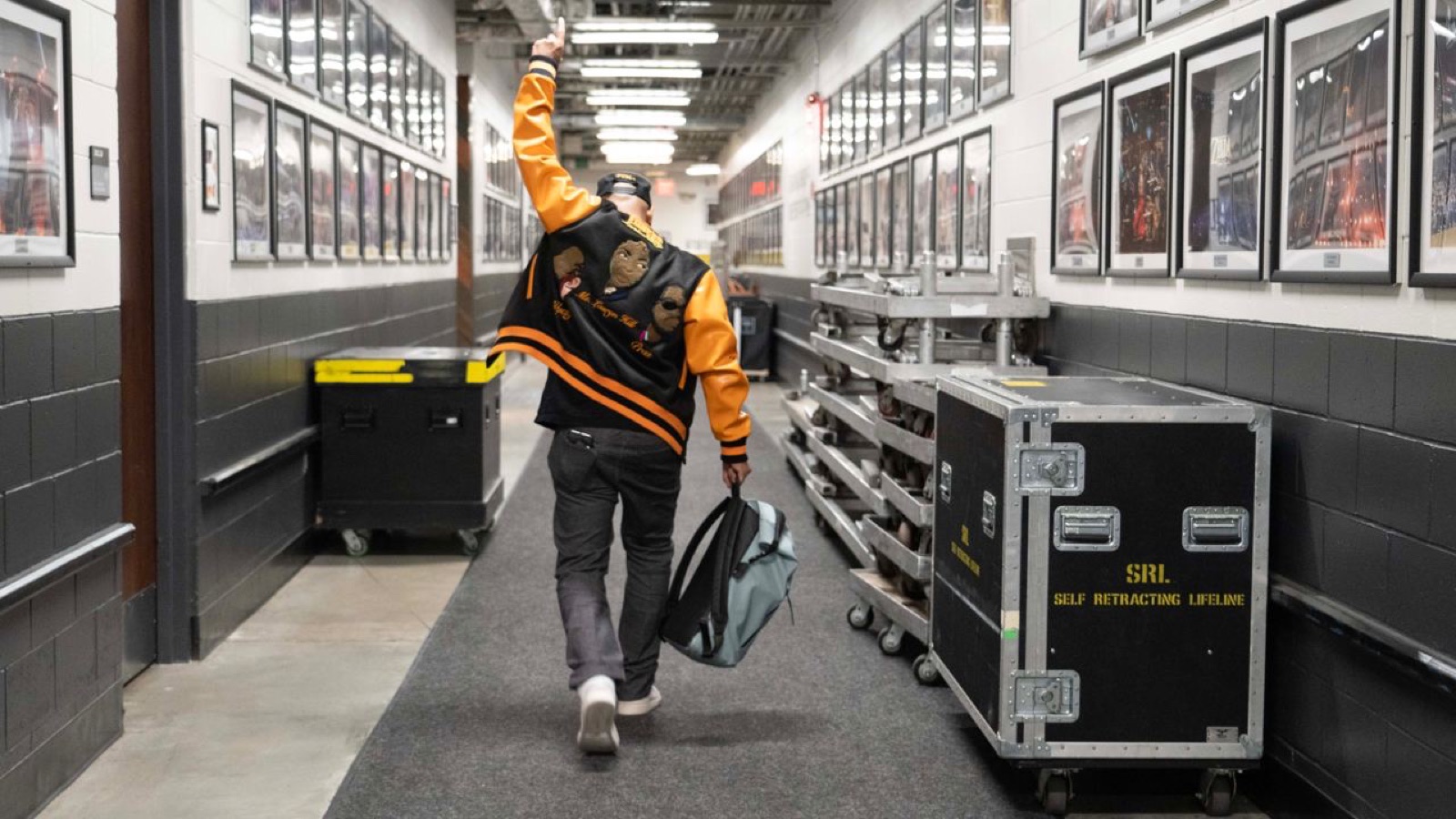 Artist walking down a backstage hallway past road cases